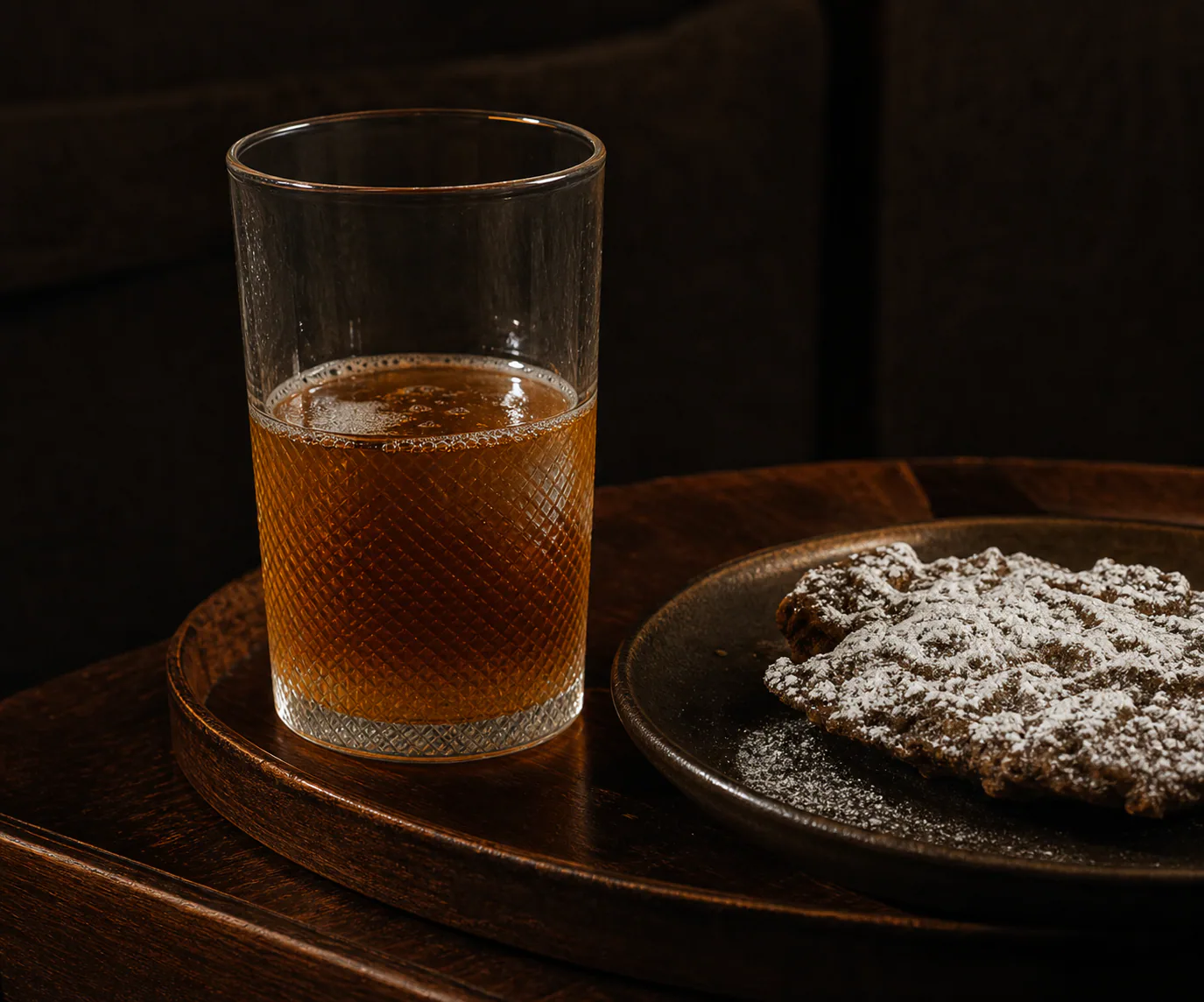 A small glass and local snack beside a dark wood minibar