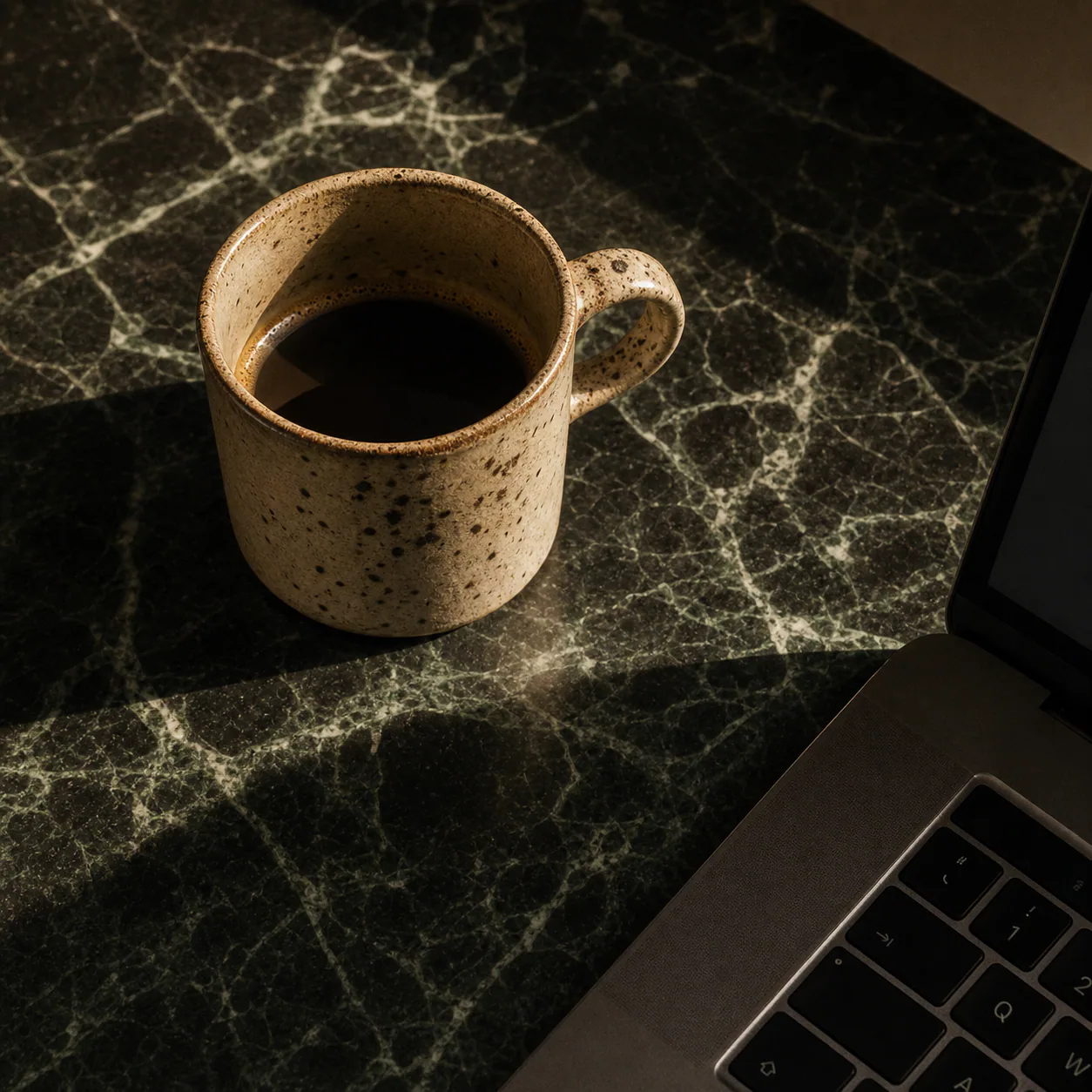Coffee and laptop on a shared marble table