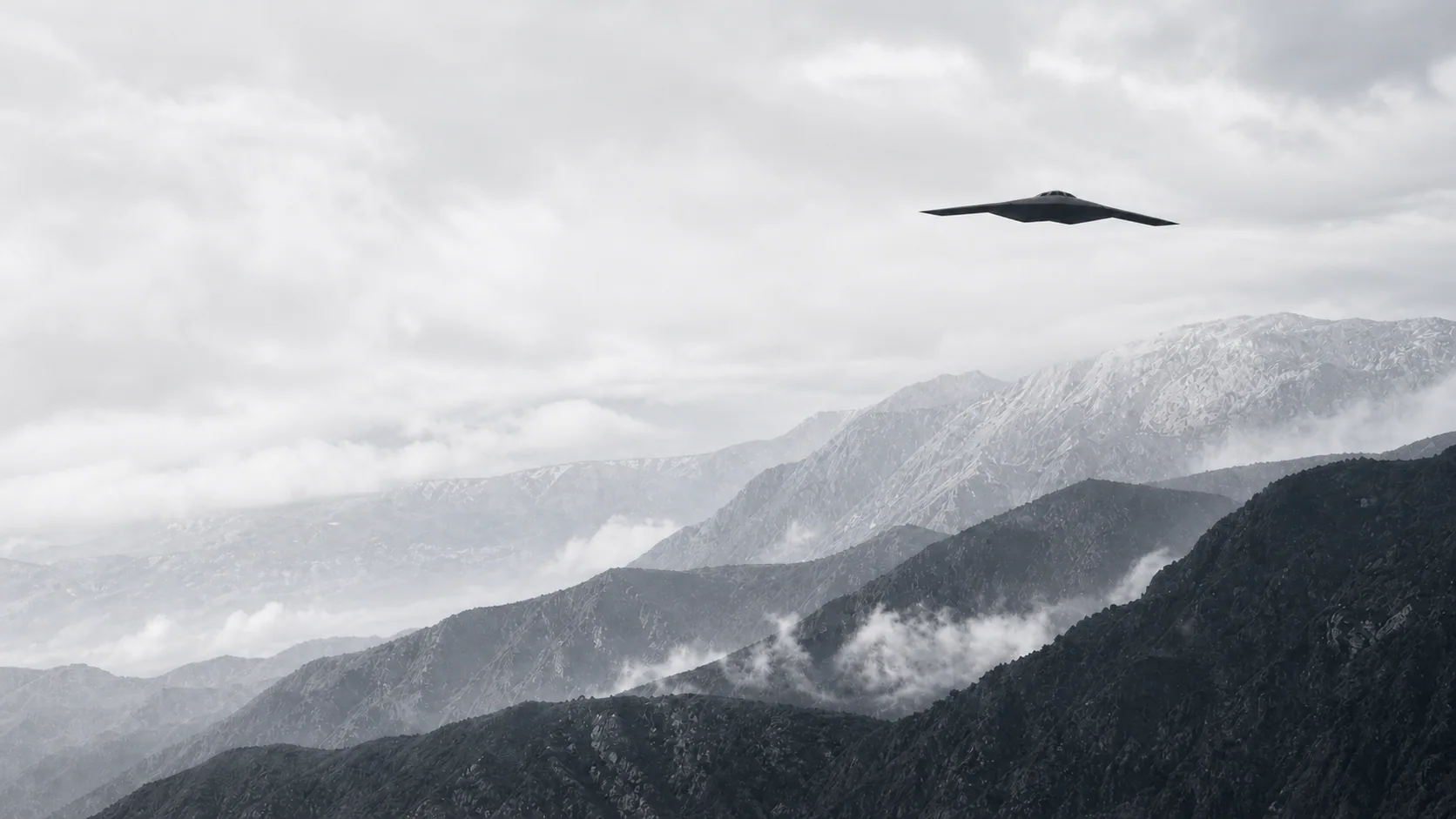 Flying-wing aircraft crossing a misted mountain range