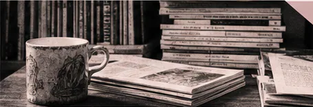Editorial desk with books, a cup, and marked-up pages