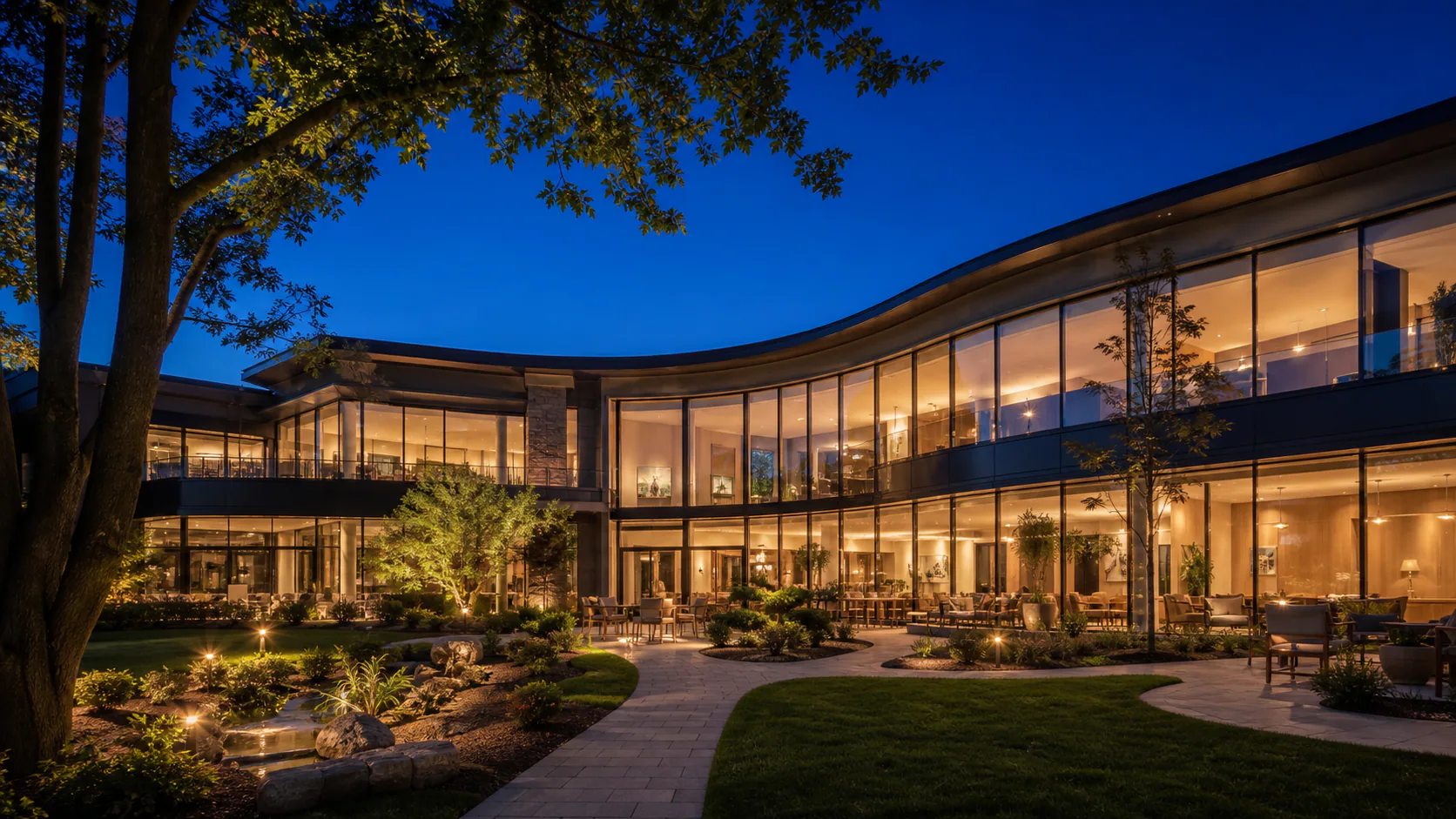 Curved contemporary residence illuminated in a night garden