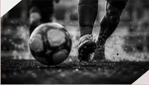 Footballer controlling the ball on a wet pitch